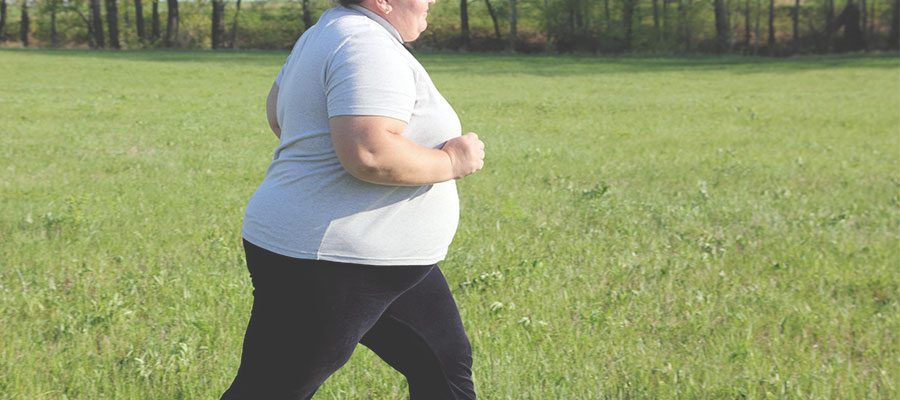 Mulher obesa corre em parque em dia ensolarado