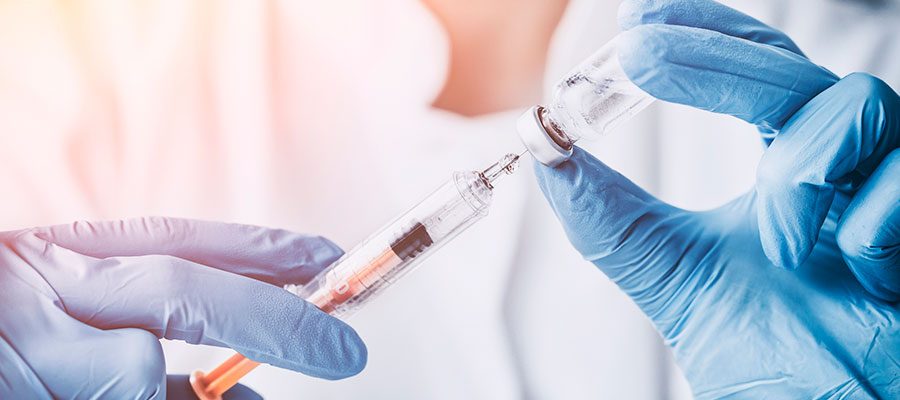 Cientista no laboratório segurando seringa e vacina