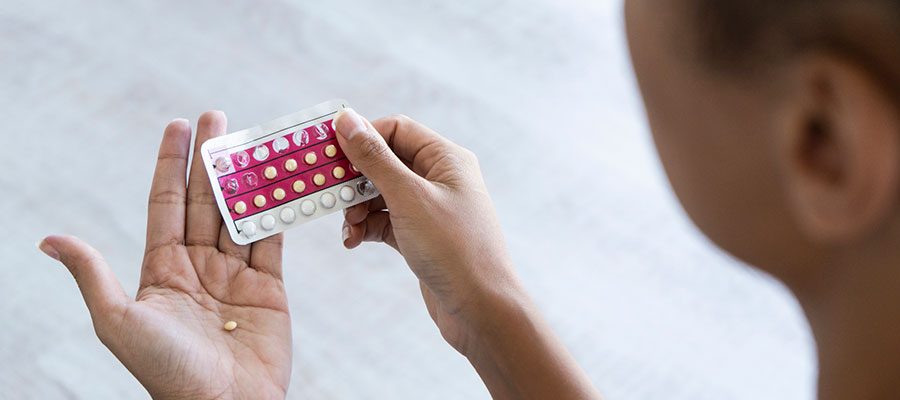 Mulher segurando cartela de pílula anticoncepcional