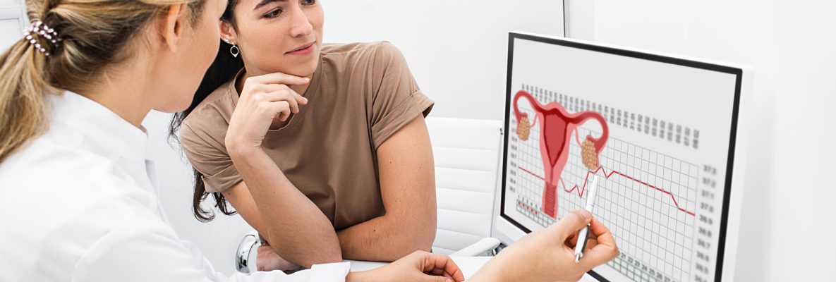 Ginecologista se comunica com sua paciente, indicando o ciclo menstrual no monitor