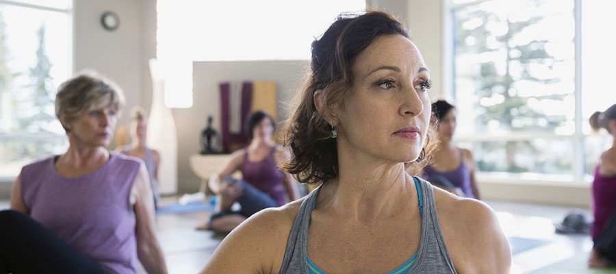 Mulher se exercitando em sala com outras mulheres, beneficiando o tratamento de câncer