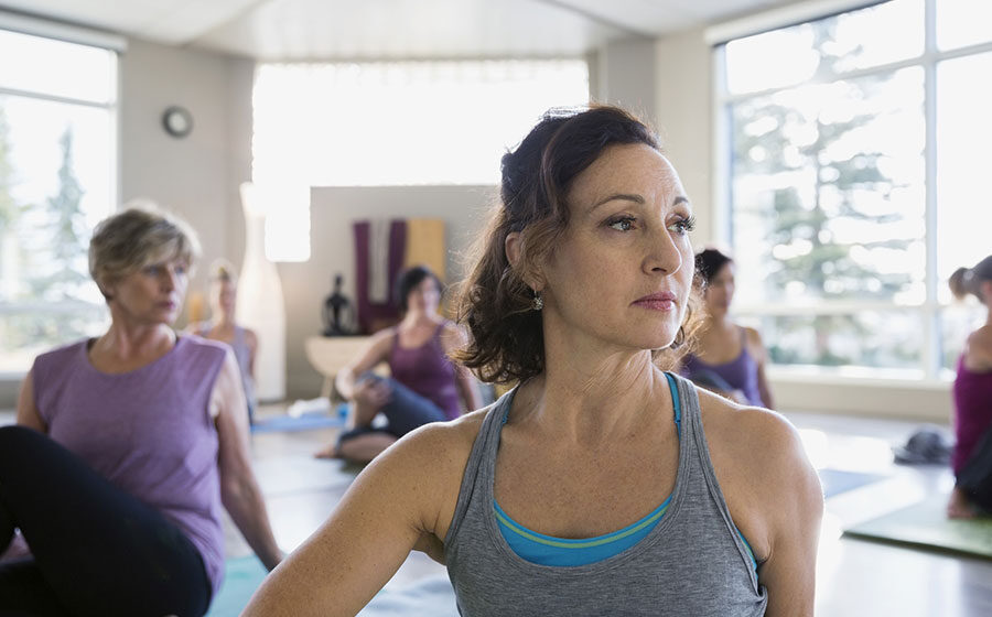 Mulher se exercitando em sala com outras mulheres, beneficiando o tratamento de câncer
