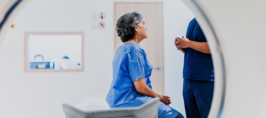 Mulher idosa conversando com uma enfermeira e realizando exame